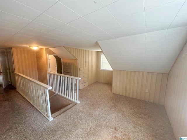 bonus room featuring lofted ceiling, carpet flooring, and wooden walls