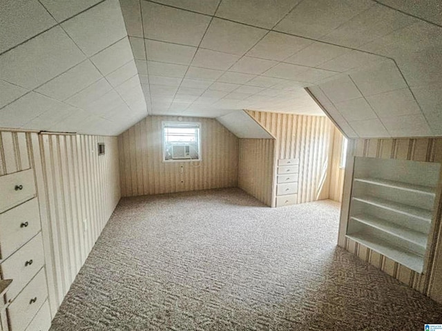 additional living space with lofted ceiling, wood walls, and carpet