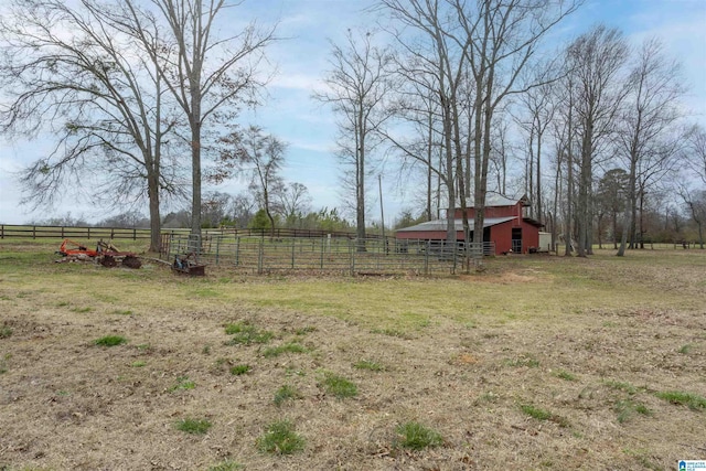 view of yard with a rural view, an outdoor structure, a barn, fence, and an exterior structure