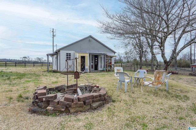 exterior space with an outdoor fire pit, fence, an outdoor structure, and a lawn