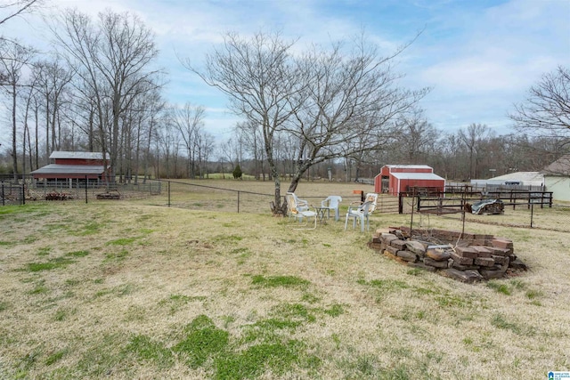 view of yard featuring a shed, a rural view, fence, and an outbuilding