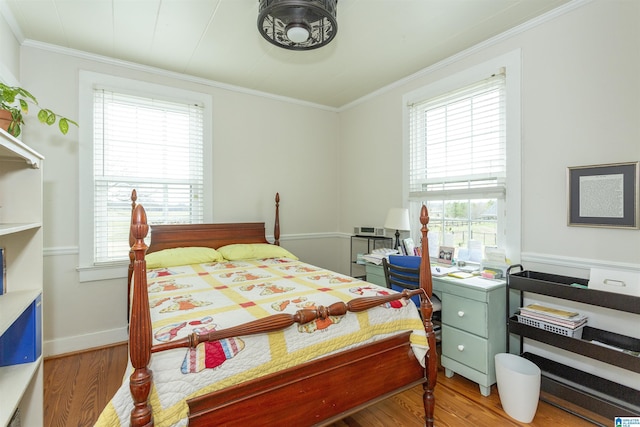 bedroom with ornamental molding, wood finished floors, and baseboards