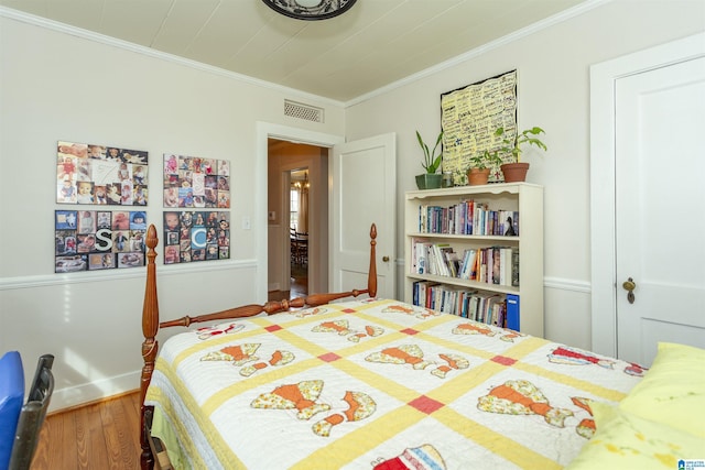 bedroom featuring baseboards, crown molding, visible vents, and wood finished floors