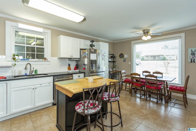 kitchen with stainless steel appliances, crown molding, a sink, and backsplash