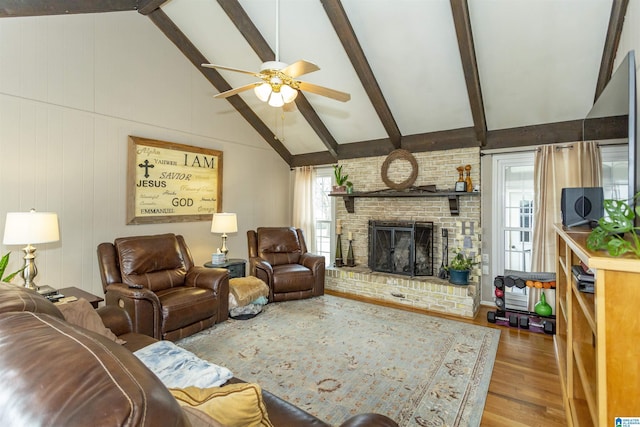 living area with a ceiling fan, wood finished floors, a brick fireplace, high vaulted ceiling, and beam ceiling