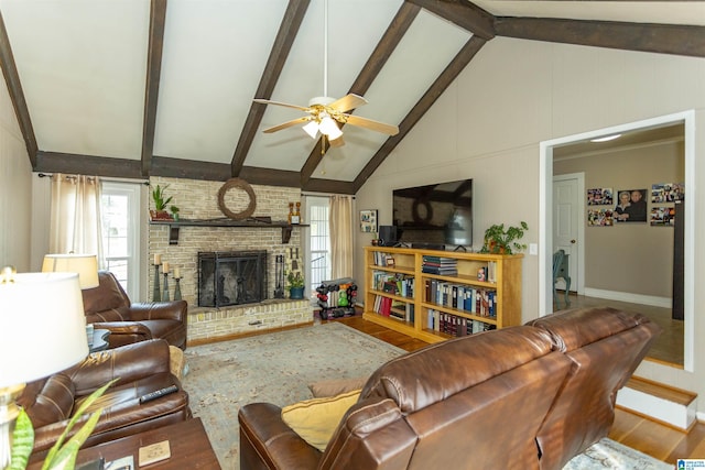 living area with a ceiling fan, a fireplace, beamed ceiling, and wood finished floors