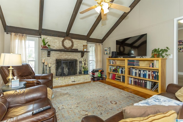 living area with lofted ceiling with beams, a brick fireplace, wood finished floors, and a healthy amount of sunlight