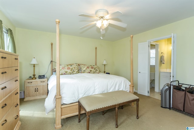 bedroom with ensuite bath, a ceiling fan, and light colored carpet