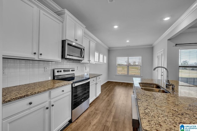 kitchen featuring crown molding, tasteful backsplash, appliances with stainless steel finishes, a sink, and wood finished floors