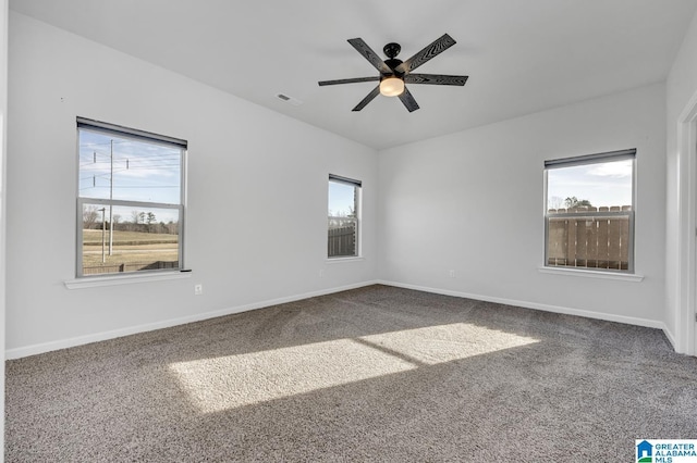 empty room featuring ceiling fan, carpet floors, visible vents, and baseboards