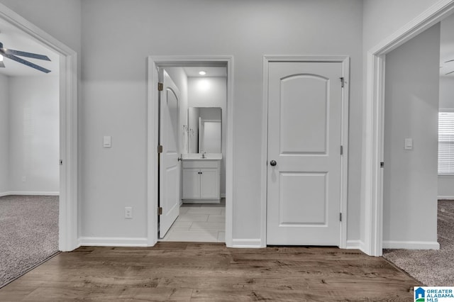 hall with carpet floors, baseboards, and wood finished floors