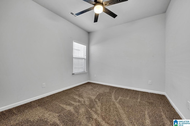 spare room with dark colored carpet, a ceiling fan, visible vents, and baseboards