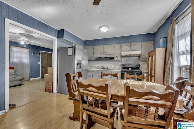 dining area with a ceiling fan, light wood-type flooring, and a textured ceiling