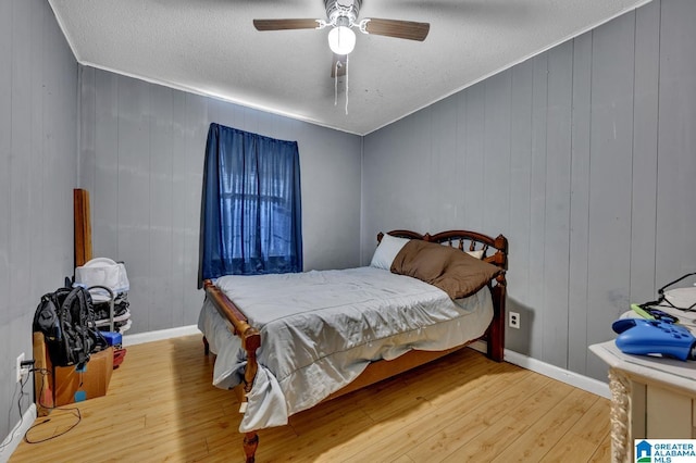 bedroom featuring ceiling fan, a textured ceiling, wood finished floors, and baseboards