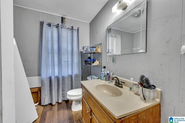 bathroom with toilet, a textured ceiling, vanity, and wood finished floors