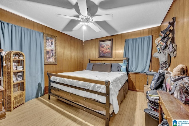 bedroom featuring light wood-type flooring, wood walls, and ceiling fan