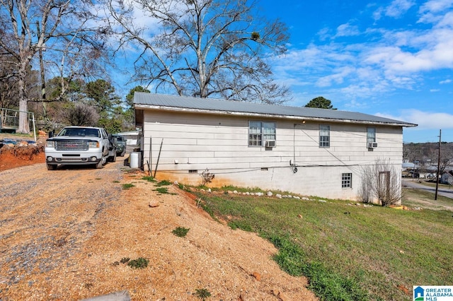 view of property exterior with metal roof, driveway, crawl space, and a lawn