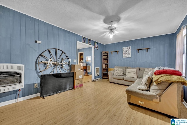 living area with a textured ceiling, heating unit, and wood finished floors