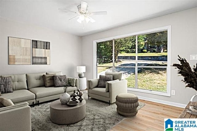 living room featuring a ceiling fan, baseboards, and wood finished floors