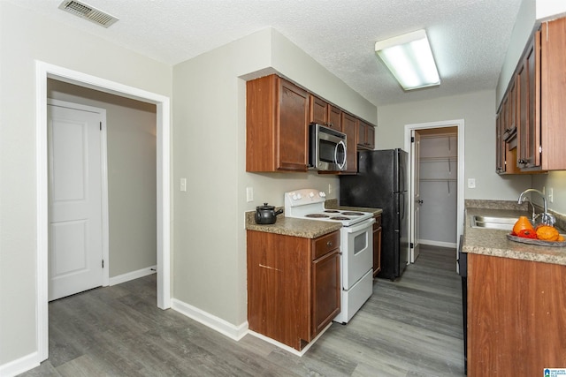 kitchen featuring white range with electric cooktop, wood finished floors, a sink, visible vents, and stainless steel microwave