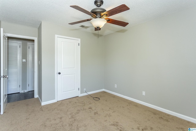 unfurnished bedroom featuring baseboards, visible vents, ceiling fan, a textured ceiling, and carpet flooring