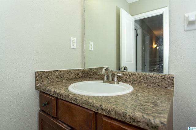 bathroom with a textured wall and vanity