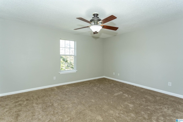 spare room with a textured ceiling, dark carpet, a ceiling fan, and baseboards