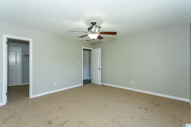 unfurnished bedroom with a textured ceiling, a spacious closet, carpet flooring, and baseboards