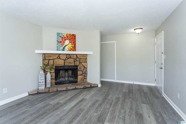 unfurnished living room with a fireplace, a textured ceiling, baseboards, and wood finished floors