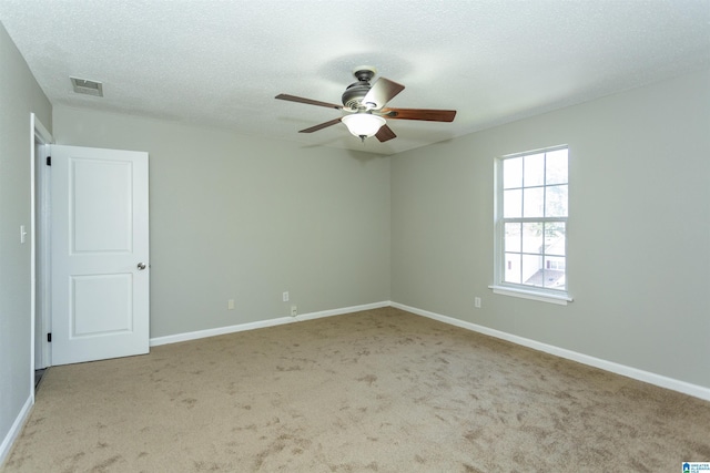 empty room featuring carpet, visible vents, a textured ceiling, and baseboards