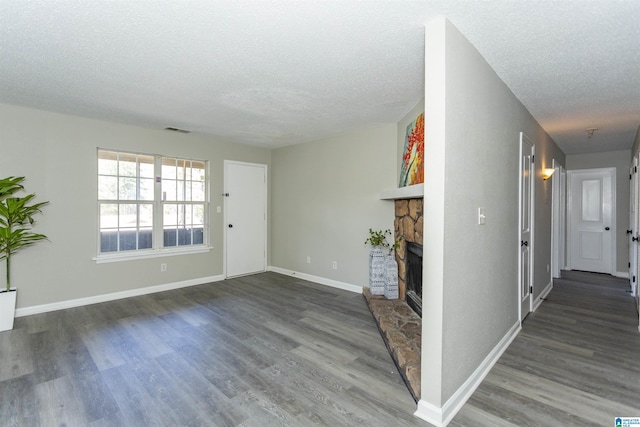 unfurnished living room with a textured ceiling, a fireplace, wood finished floors, and visible vents