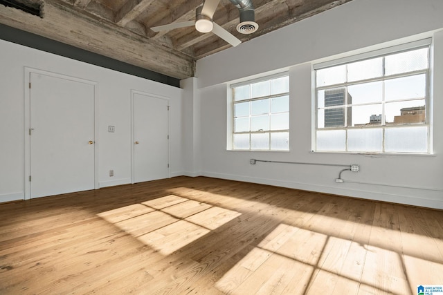 unfurnished bedroom featuring a ceiling fan, visible vents, baseboards, and hardwood / wood-style flooring