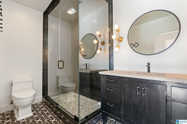 bathroom with toilet, a shower stall, baseboards, and vanity