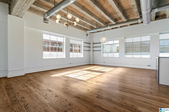 empty room featuring baseboards, wood-type flooring, visible vents, and a notable chandelier