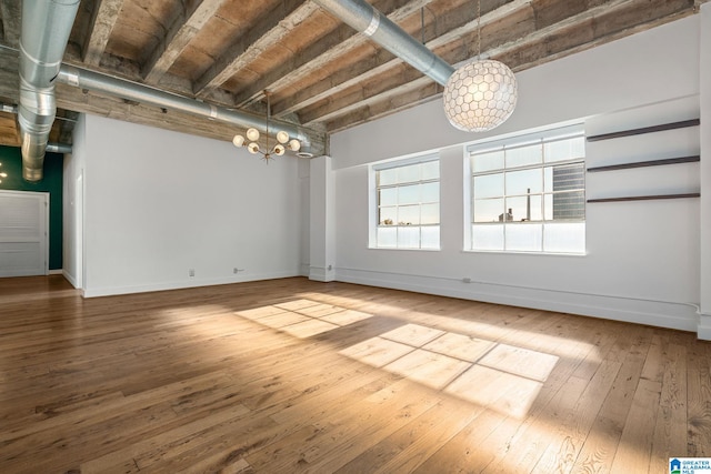 spare room featuring an inviting chandelier, baseboards, and hardwood / wood-style floors