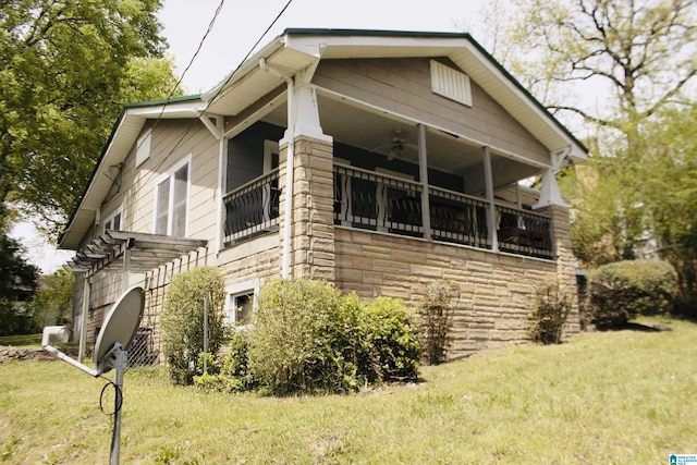 view of property exterior featuring ceiling fan, a yard, and stone siding