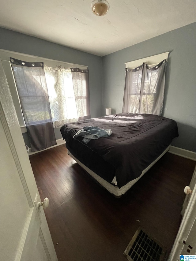 bedroom with dark wood-style floors and baseboards