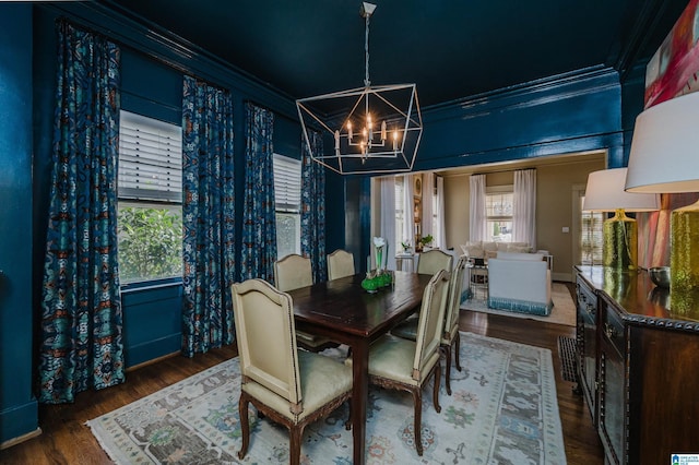 dining area with wood finished floors, a chandelier, and ornamental molding