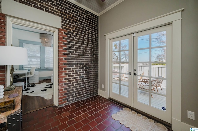 entryway featuring brick wall, crown molding, baseboards, french doors, and brick floor