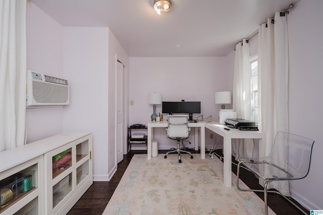 office area featuring dark wood finished floors, a wall unit AC, and baseboards