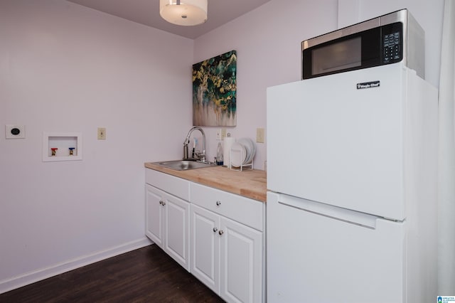 kitchen featuring a sink, stainless steel microwave, freestanding refrigerator, butcher block counters, and dark wood-style flooring