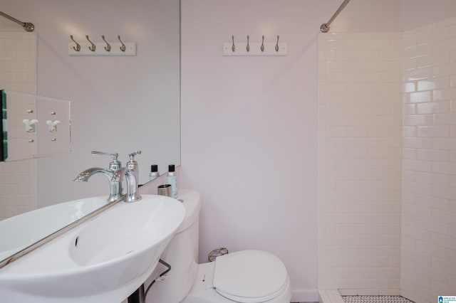 bathroom featuring a sink, toilet, and tiled shower