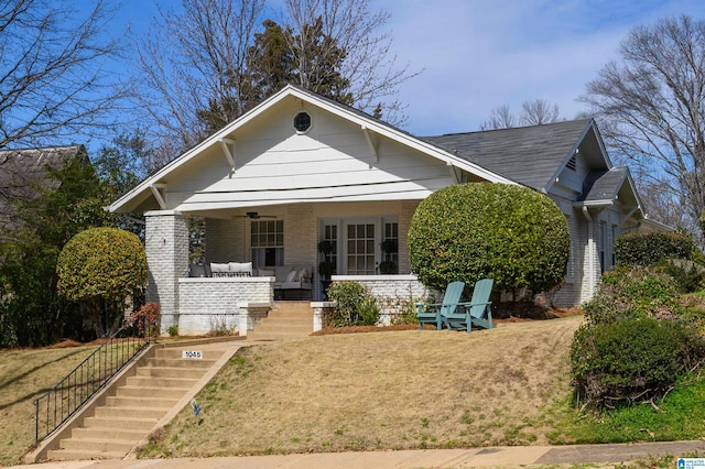 view of front of house with stairway, a porch, ceiling fan, a front lawn, and brick siding