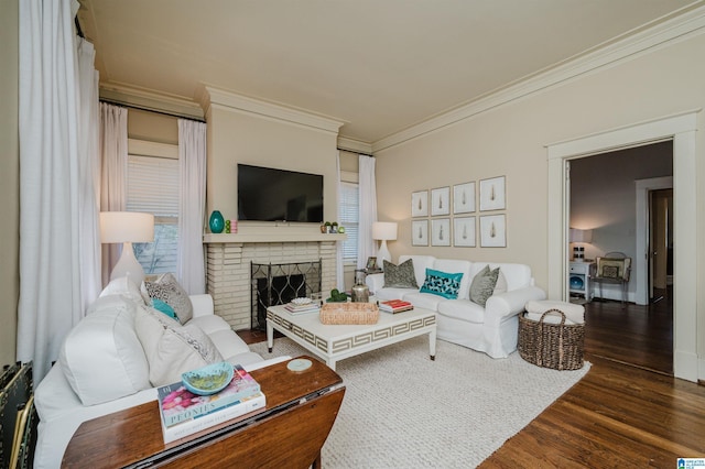 living area featuring a healthy amount of sunlight, a brick fireplace, crown molding, and wood finished floors