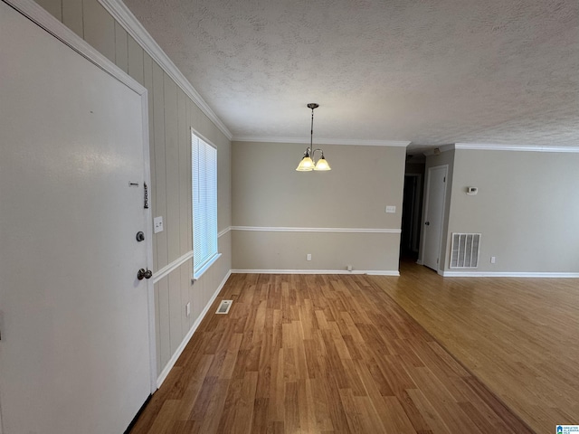 spare room with visible vents, a notable chandelier, light wood-style flooring, and a textured ceiling