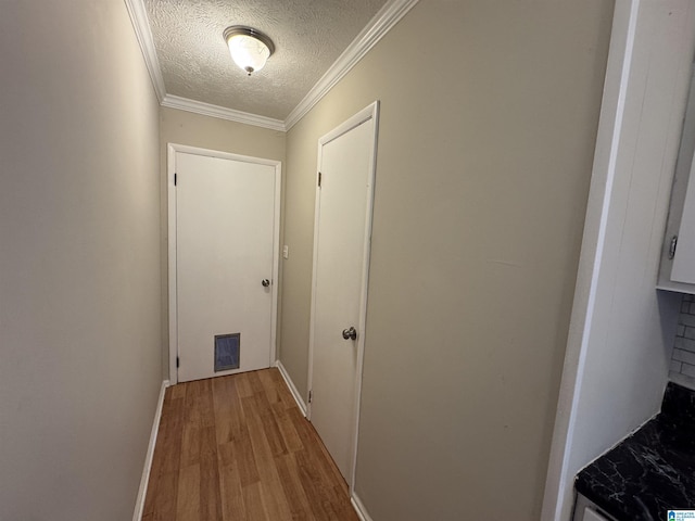 hallway featuring ornamental molding, visible vents, a textured ceiling, and light wood finished floors