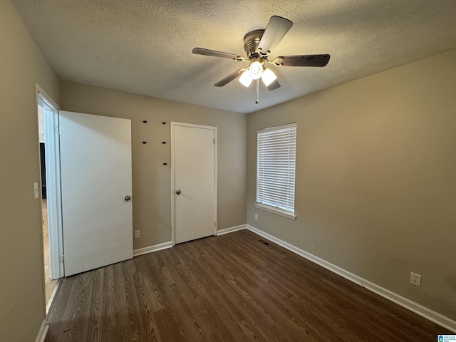 unfurnished bedroom with a ceiling fan, baseboards, dark wood finished floors, and a textured ceiling