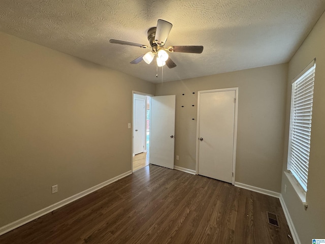 unfurnished bedroom featuring visible vents, baseboards, a ceiling fan, dark wood-style flooring, and a textured ceiling