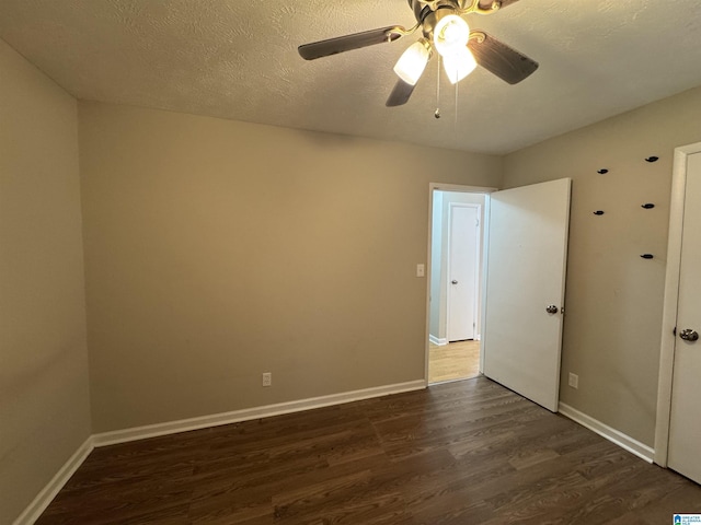 unfurnished room with dark wood-type flooring, a textured ceiling, and baseboards