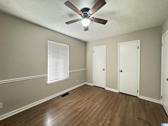 unfurnished bedroom with a textured ceiling, wood finished floors, visible vents, and baseboards